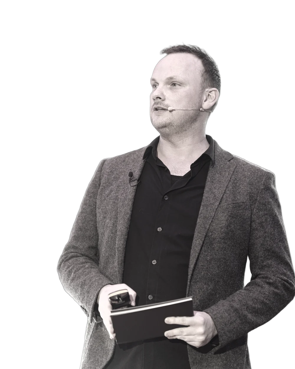 Arne Pohl spricht auf einer Bühne, mit Headset-Mikrofon und Unterlagen in der Hand.